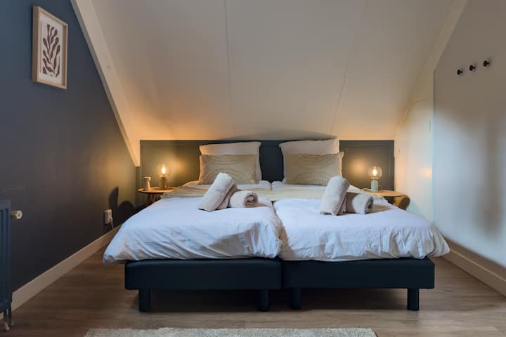 ในห้องนอนด้านหลังมีเตียงเดี่ยวสองเตียงพร้อมฟูกนอนน่ารักๆ ถัดจากเตียงคุณจะพบโคมไฟข้างเตียงที่หรี่แสงได้