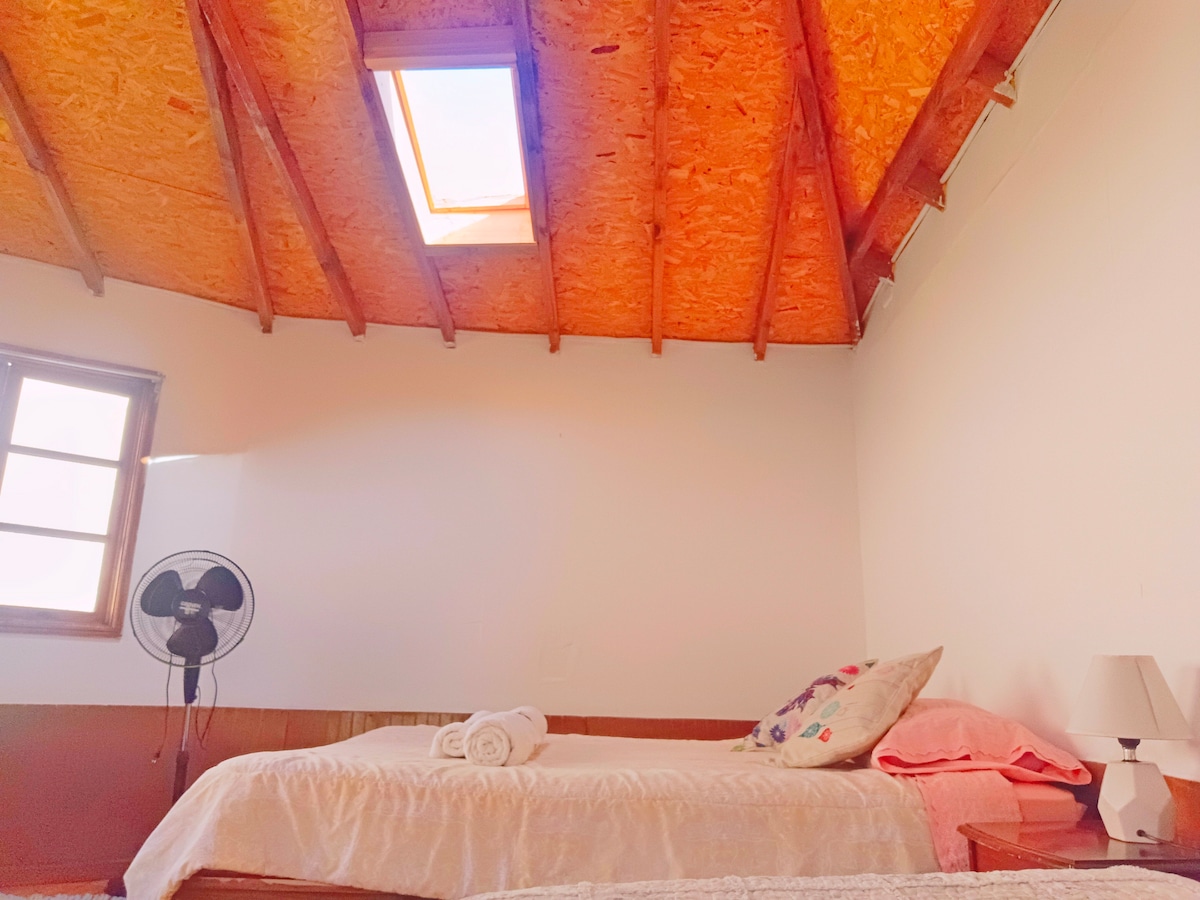 La cama matrimonial queda bajo la lucarna, en la noche podrás ver las estrellas y la ventana del frente a la cama tiene vista a los cerros y al cielo. Te entregamos mantas extras