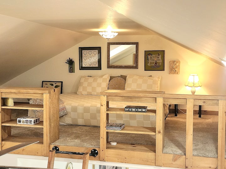 Airy loft with a queen bed and a view of the heart of the cottage
The second loft features a cozy queen-size bed overlooking the kitchen and main living area below. It’s a light-filled, open space that still feels tucked away.