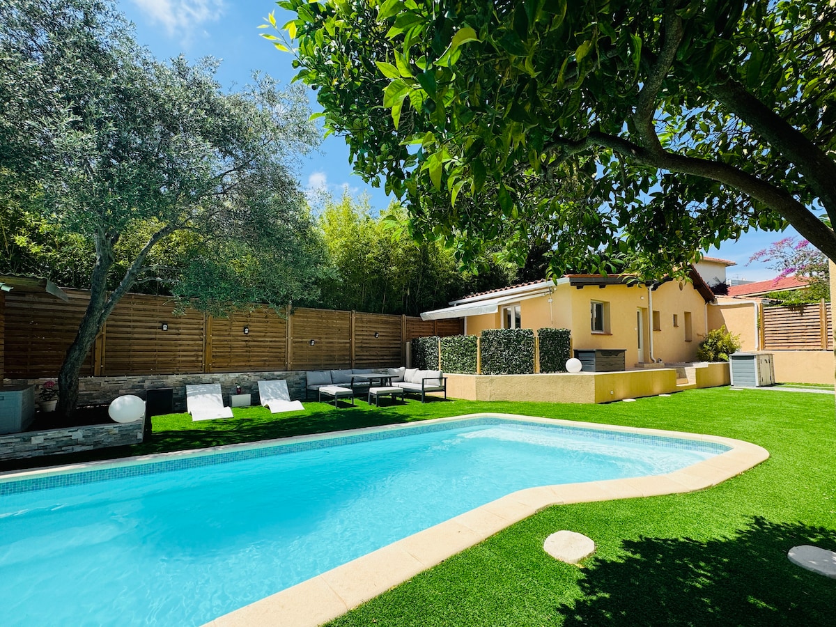 A private swimming pool is framed by well-maintained greenery, with comfortable lounge chairs positioned nearby. Sunlight reflects off the clear water, while the surrounding area features a cozy seating arrangement and a serene ambiance, ideal for relaxation.