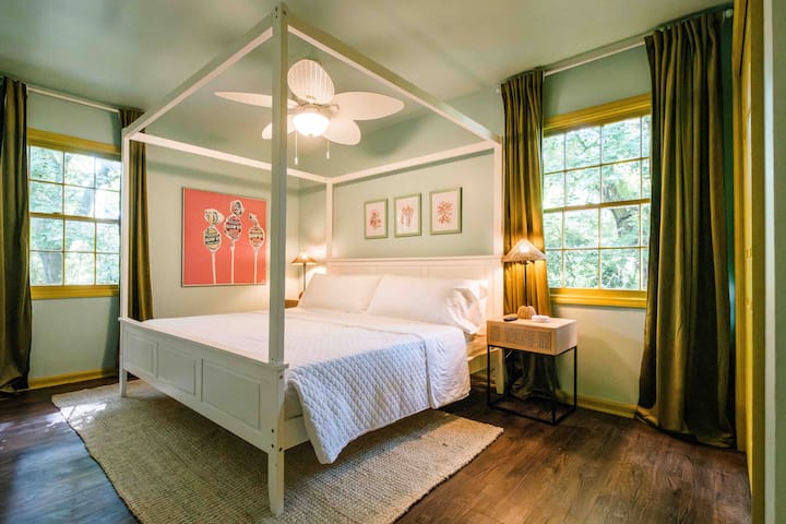 A beautiful upstairs primary bedroom with a canopy king bed, very comfortable mattress, blackout curtains, and ensuite bathroom w/shower