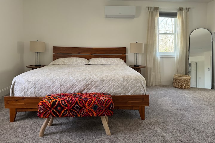 חדר שינה ראשי מרווח בגודל קינג סייז עם חדר רחצה פרטי עם שירותים.