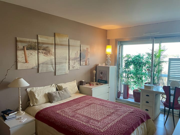 Amplia habitación en logia con cama doble, escritorio y perchero para colgar la ropa.
