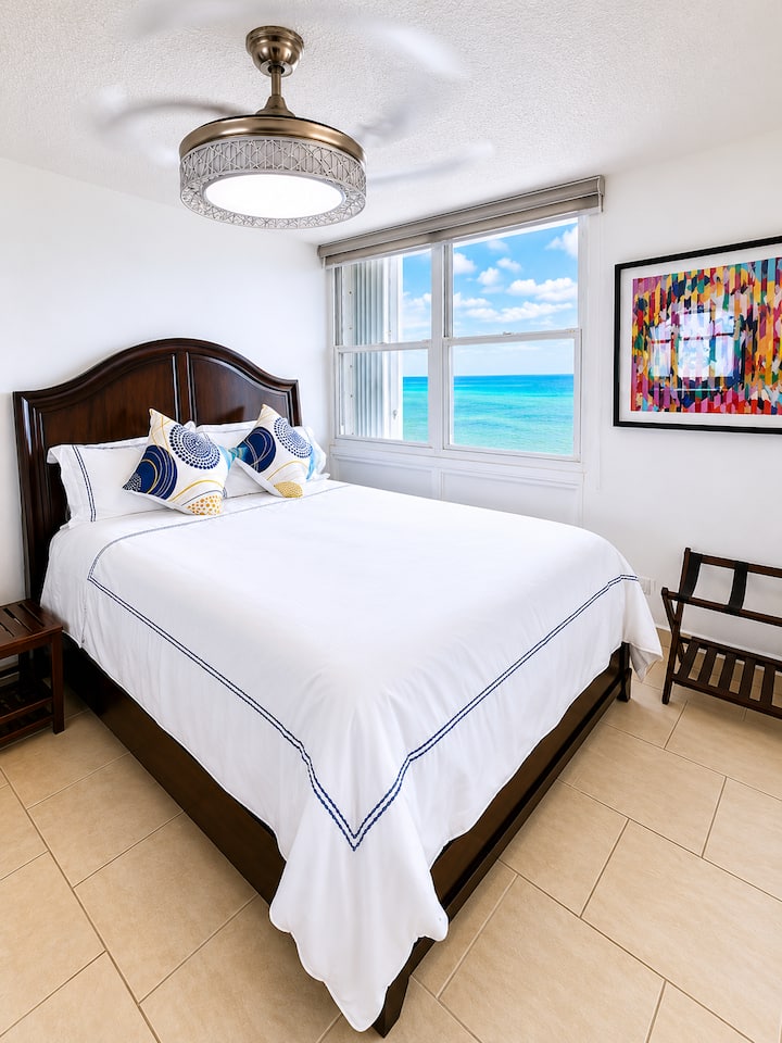 A bright and inviting bedroom featuring a comfortable queen-size bed, coastal-inspired décor, and soothing blue accents. The perfect space to relax and recharge after a day of exploring Puerto Rico.