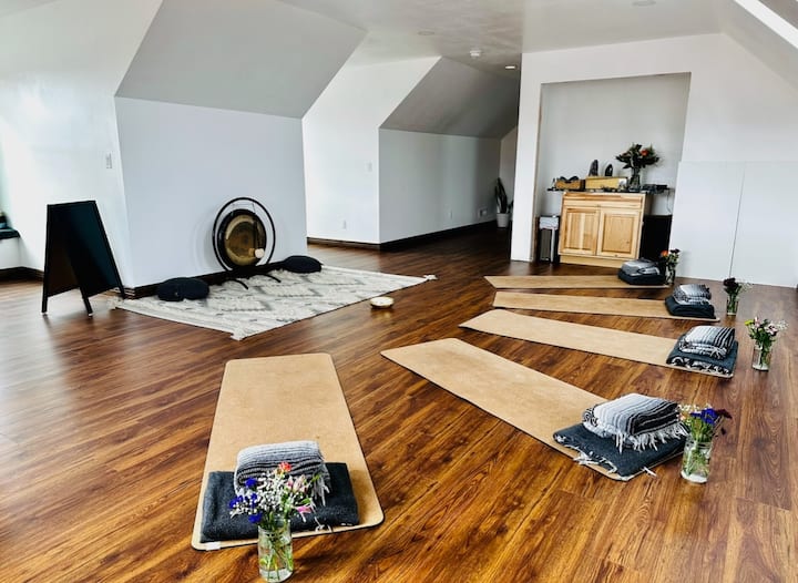 The upstairs sky room is set up for a yoga retreat in this photo. This room is an open space for events, meetings, play area, …  and it has two queen Murphy beds for sleeping arrangements. 