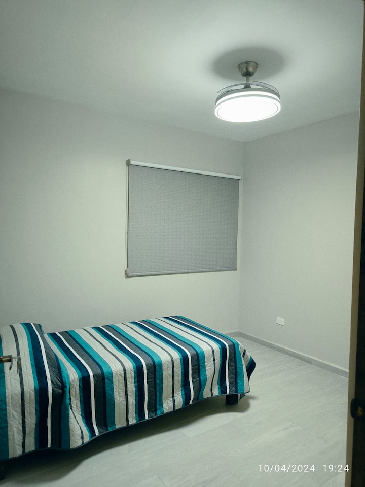 Chambre  spacieuse avec un lit simple, dispose d'un bon éclairage et d'un ventilateur rétractable avec télécommande pour sélectionner différents modes d'éclairage et de ventilation.