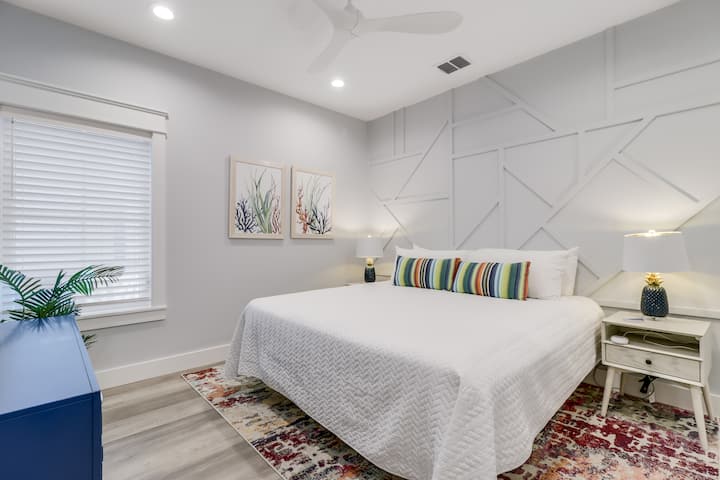 Sprofonda tra le lenzuola bianche e fresche della tua camera da letto moderna, caratterizzata da eleganti opere d'arte geometriche alle pareti e da dettagli in stile costiero, per notti tranquille.