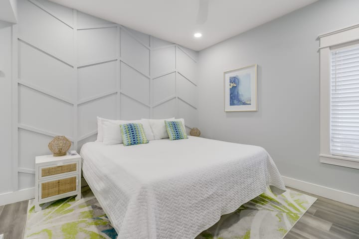 Lasciati avvolgere da un sonno tranquillo nella tua camera da letto luminosa, con lenzuola bianche e fresche e un moderno design geometrico sulle pareti che crea un rifugio rilassante.