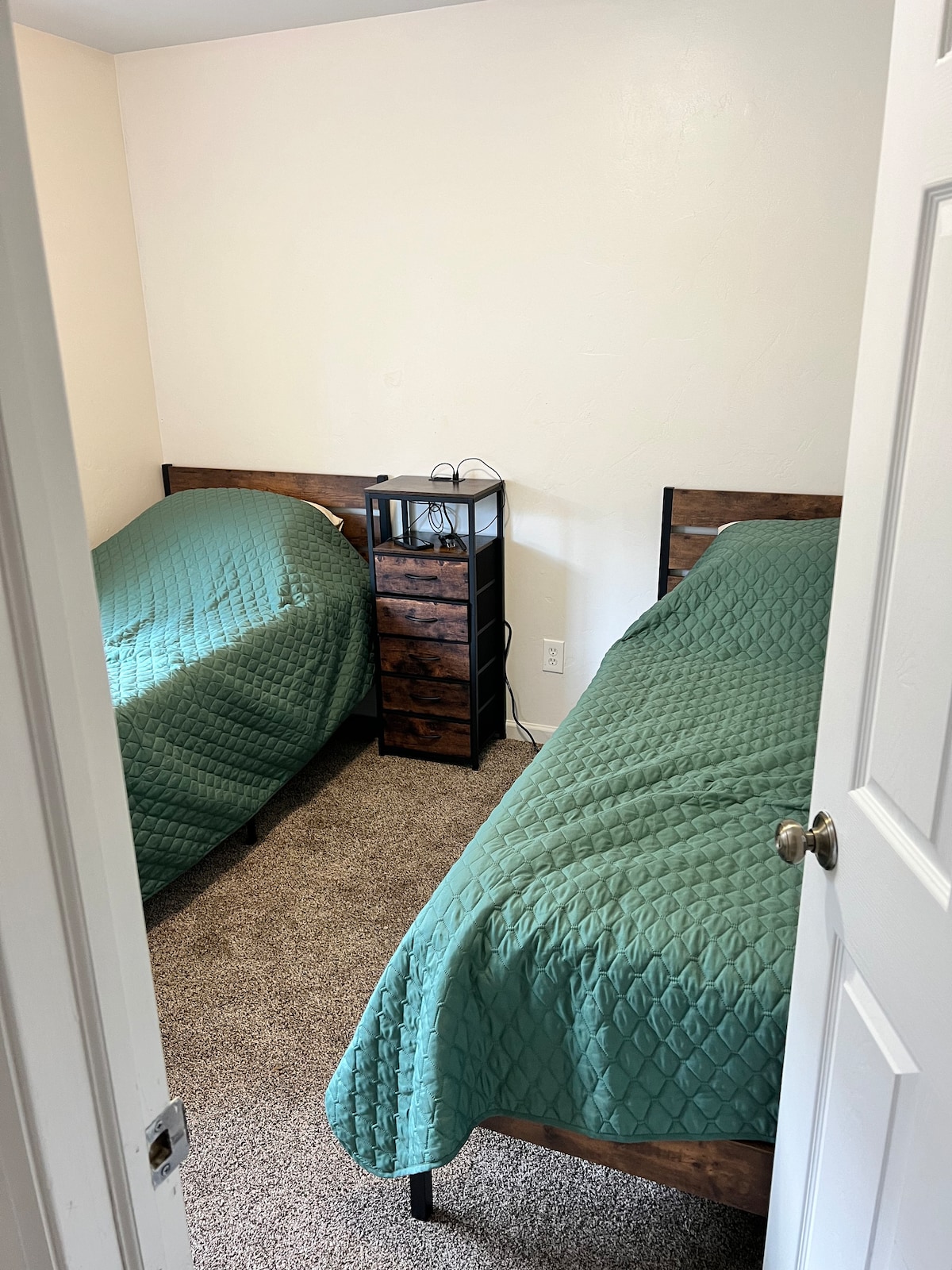 Two twin beds with 2 short dressers and charging plugs. 
