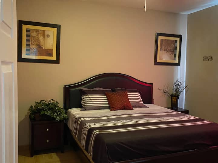Chambre principale spacieuse dotée d'un lit confortable de très grand format avec un matelas en mousse à mémoire de forme, d'une télévision intelligente, d'une commode et d'un accès direct à une salle de bain privée. Profitez d'une retraite relaxante avec beaucoup d'espace et des commodités modernes pour un séjour reposant. ️✨