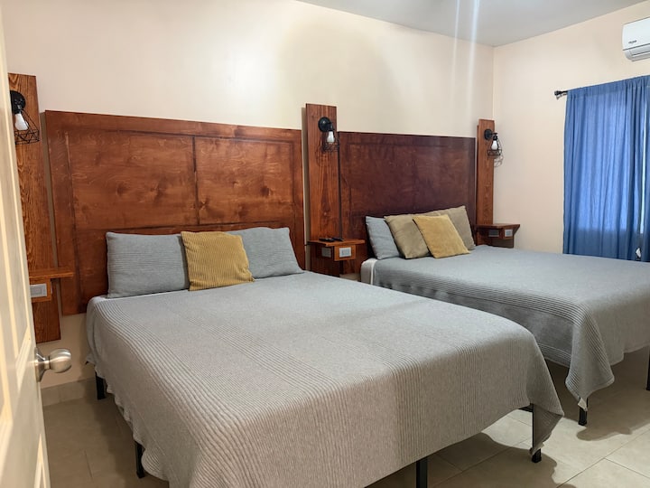 Chambre spacieuse avec 2 lits confortables (grand lit) dotés de matelas en mousse à mémoire de forme, une télévision intelligente, une commode, des tables de chevet avec des ports de recharge USB et USB-C, et un climatiseur mini-split silencieux. Parfaite pour se détendre et profiter d'un séjour reposant. ️✨