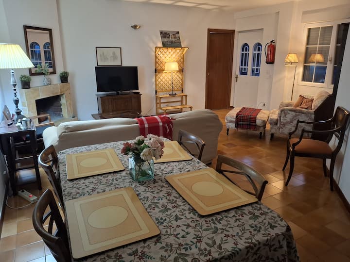 Salón-comedor con mesa puesta, sofás y sillón de mimbre: zona amplia para compartir comidas y sobremesas.
