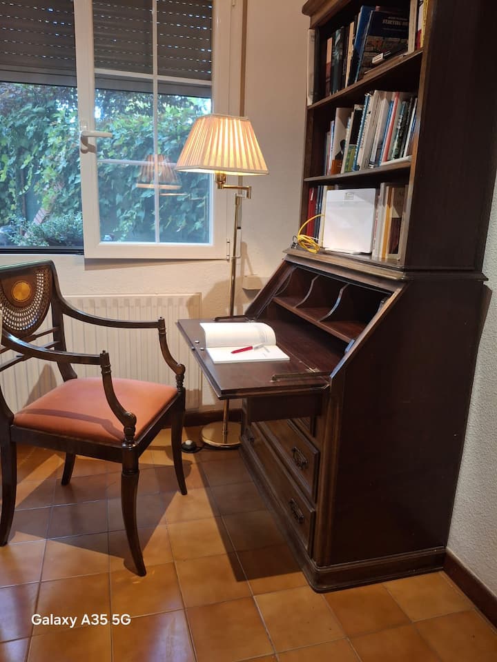 Zona de trabajo con secreter de madera y butaca junto a la ventana: perfecta para teletrabajar.
