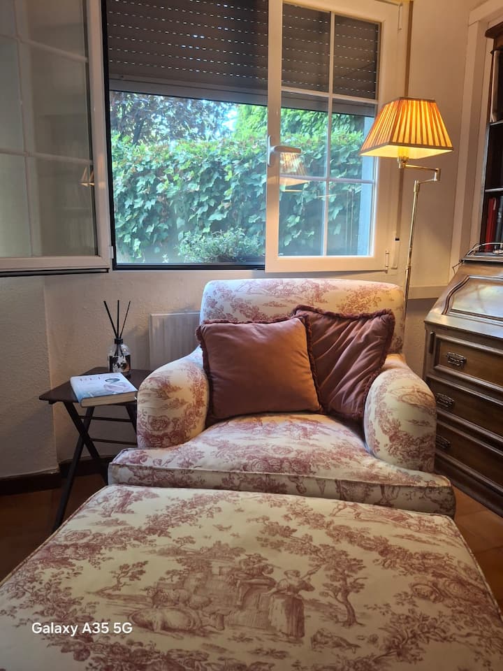 Butaca junto a la ventana con vistas al jardín: el lugar perfecto para leer con calma.