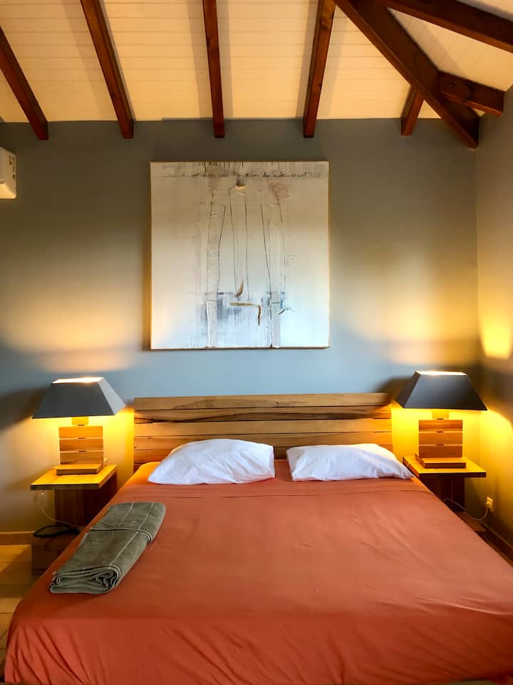Chambre parentale très confortable avec climatisation, espace de travail et salle de bain individuelle, double vasque et toilette.
