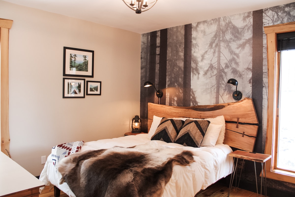 The master bedroom features a full wall mural, a spalted maple headboard and reading lamps. The Cherry end tables also feature USB charging ports at Sweet River Lodge in Tionesta