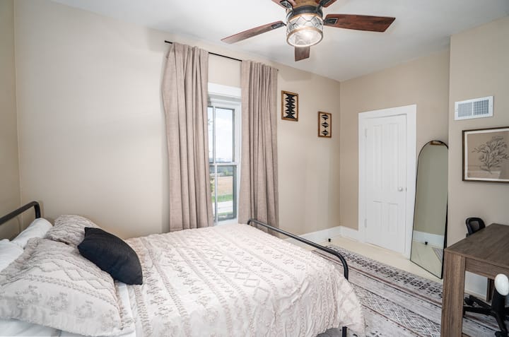 Cette photo montre l'une des chambres à l'étage avec un lit double. Cette pièce abrite également l'espace bureau avec un grand bureau pour tous vos besoins professionnels.