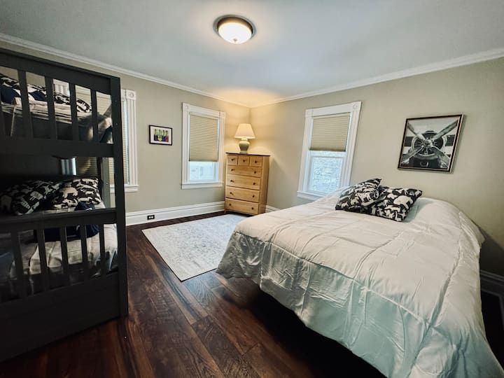 ห้องนอนชั้นสองขนาดใหญ่พร้อมเตียงควีนไซส์เตียงสองชั้นและรางตั้งอยู่ใต้เตียงสองชั้น