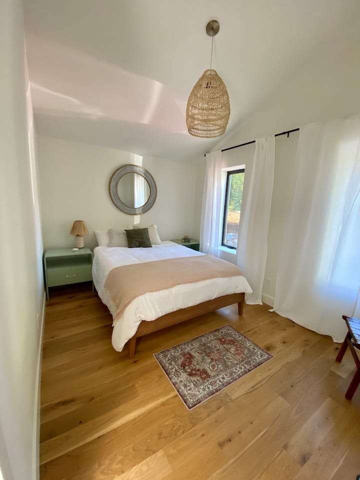 Otro dormitorio queen, cómoda grande, silla, cerca del baño del pasillo compartido en el piso principal.