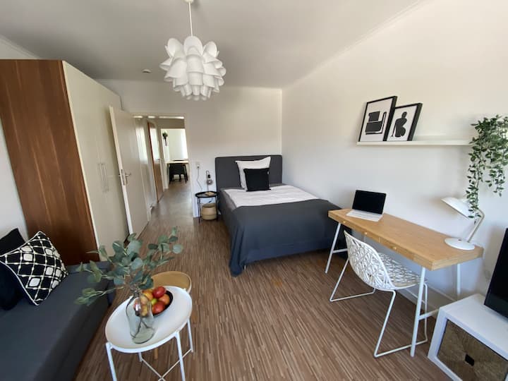 Modernes Wohn-Schlafzimmer mit Boxspringbett (1,40 m), großzügigem Schrank & integriertem Arbeitsplatz – ideal für Paare oder Alleinreisende