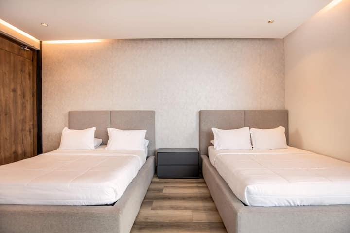 Two luxurious beds with hotel-quality linens await in this perfectly symmetrical setup—ideal for sharing without sacrificing comfort or privacy.