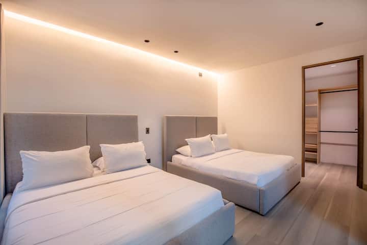 Dos lujosas camas con sábanas de calidad hotelera te esperan en esta configuración perfectamente simétrica, ideal para compartir sin sacrificar la comodidad o la privacidad.