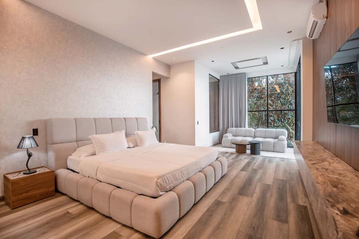 Duerme con estilo con sábanas de lujo, elegantes mesitas de noche y una paleta de colores relajantes que marca la pauta para la relajación y la privacidad.