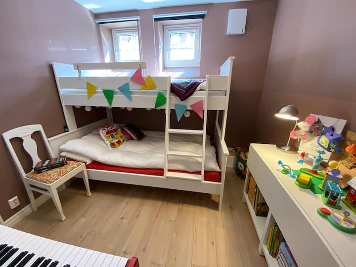 Chumba cha watoto kilicho na ghorofa ya familia. Kitanda cha chini kina upana wa sentimita 120, wakati kitanda kilicho juu kina upana wa sentimita 90. Hapa, watu wazima wawili au mtu mzima mmoja na watoto wawili wanaweza kulala kwa starehe. 