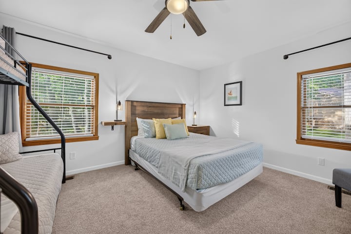 Queen bed and a twin over full bunk bed, plus twin floor mattress (room sleeps max 5 people). There's a dresser, clothing rack, ceiling fan, chair and TV. Windows have light filtering mini blinds and room darkening curtains. Bathroom is next door.