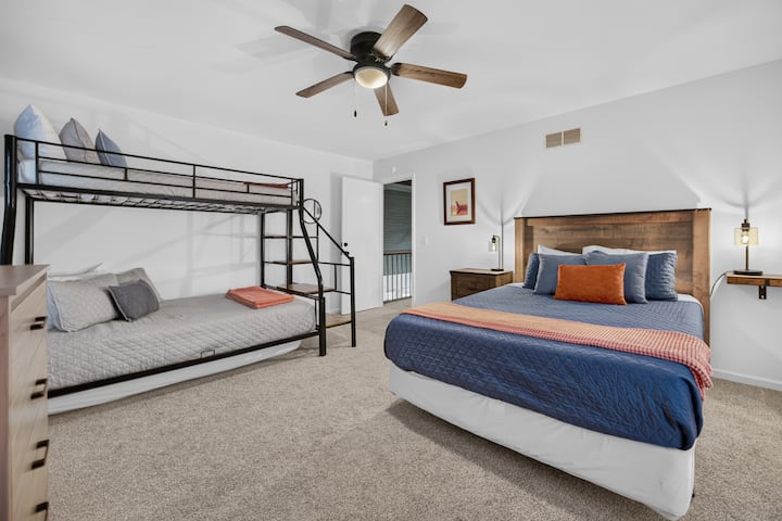 Queen bed and a twin over full bunk bed, plus twin floor mattress (room sleeps max 5 people). There's a dresser, clothing rack, ceiling fan, chair and TV. Windows have light filtering mini blinds and room darkening curtains.
