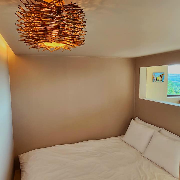 Cama tamaño queen y ropa de cama para el cuidado de la alergia en el dormitorio separada por una partición