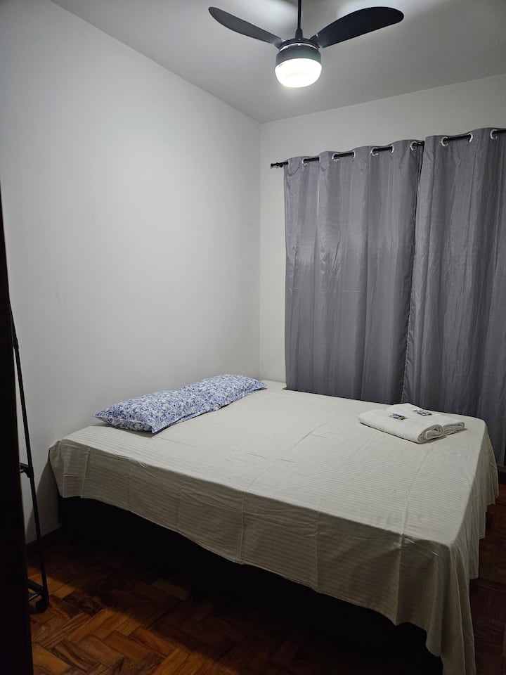 Queensize bed, plafondventilator, kleedrek, beddengoed, badhanddoek en deken om te bedekken.