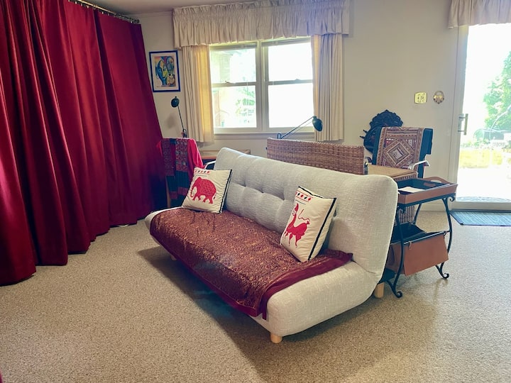 Obývacia izba na prízemí s výhľadom na rieku, gauč, ktorý sa mení na manželskú posteľ, televízor, dva stoly a vybavenie na cvičenie. Poličky na knihy s detskými knihami a hračkami. Záchranné vesty a prístup na dvor. 