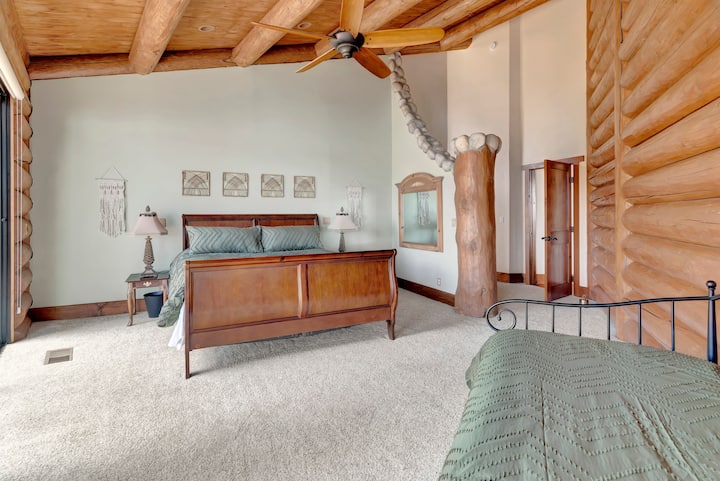 Luxurious master suite with king bed—vaulted timber ceilings, ceiling fan, elegant furnishings, and serene atmosphere