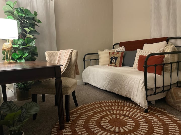 Ოთახის გამუქებული ფერები, სამუშაო სივრცე და საწოლი, რომელშიც შედის 2 ტყუპი საწოლი მეორე საძინებელში.