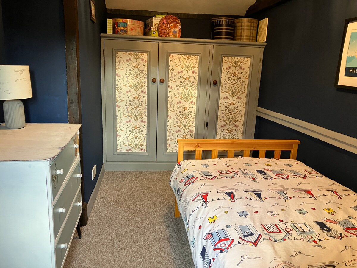 ห้องนอนธีมริมทะเลพร้อมเตียงเดี่ยวและพื้นที่เพียงพอสำหรับเสื้อผ้า ห้องนี้เข้าถึงได้จากห้องนอนคู่ 