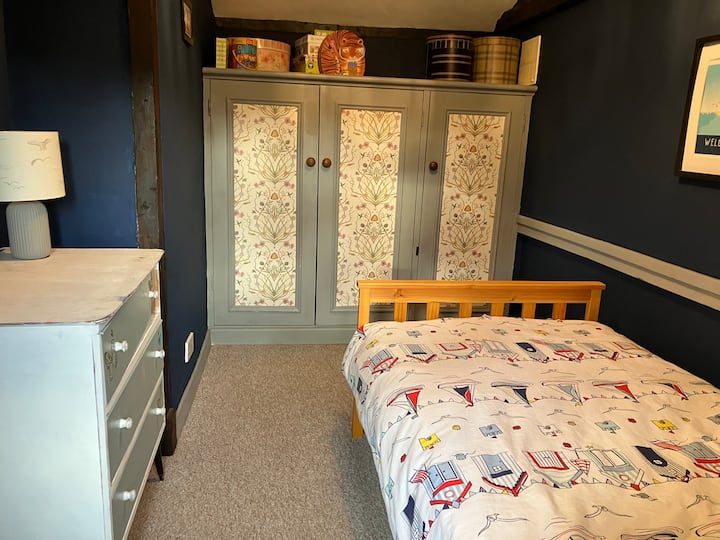 Een slaapkamer aan zee met een eenpersoonsbed en voldoende ruimte voor kleding. Deze kamer is toegankelijk vanuit de slaapkamer met tweepersoonsbed. 