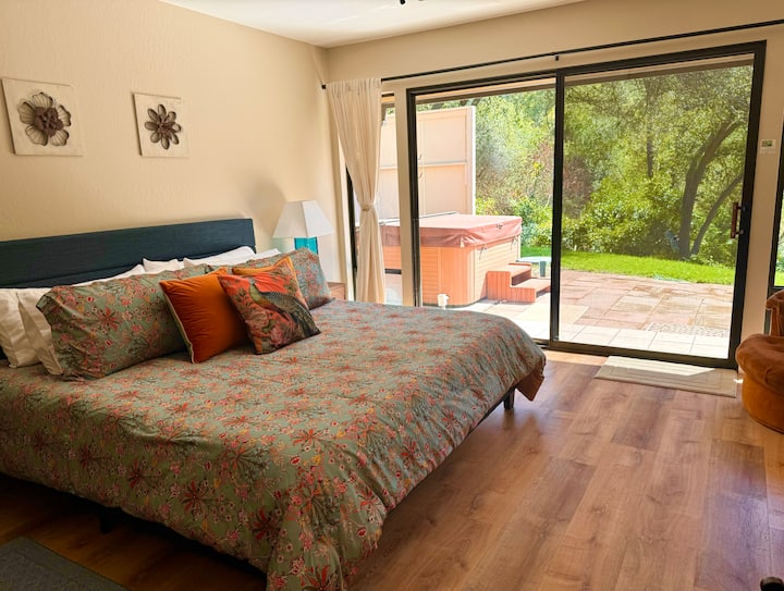 Chambre principale spacieuse et élégante avec accès direct au jacuzzi et vue sur la rivière.