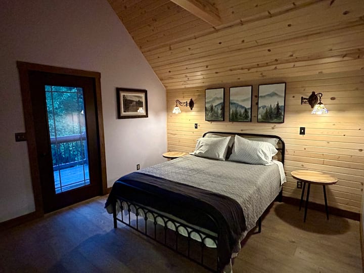Upstairs bedroom with shiplap accent wall, cathedral ceiling & private balcony. 
