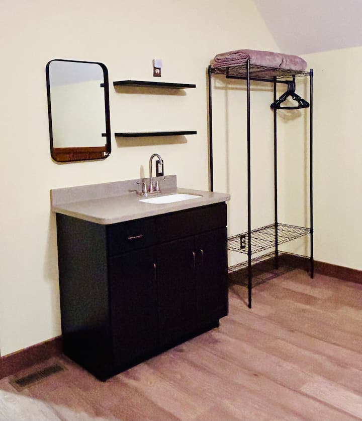 Upstairs bedroom with private balcony, in-room sink, ceiling fan, & two double beds.