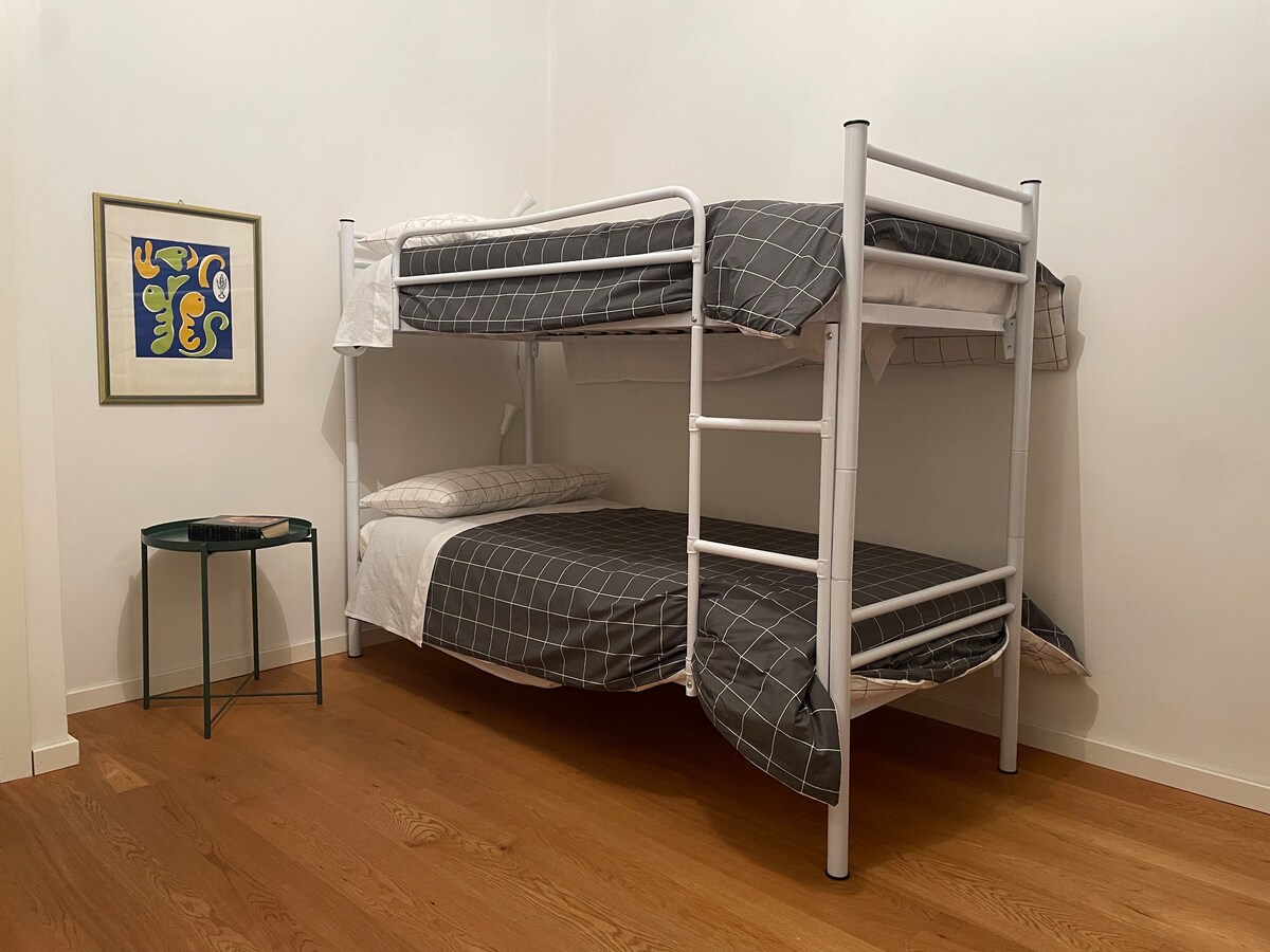 Druga spavaća soba, svijetla i tiha s pogledom na unutarnji vrt, opremljena krevetom na kat, klima-uređajem i grijalicom, s ormarom za odlaganje odjeće idealna je za ostale prijatelje ili djecu