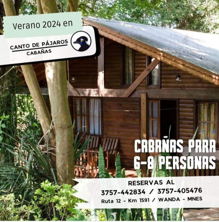 A wooden cabin is nestled among lush greenery, featuring large windows that allow natural light to illuminate the interior. A small porch with seating invites relaxation, while the surrounding trees contribute to a serene environment ideal for a peaceful getaway.
