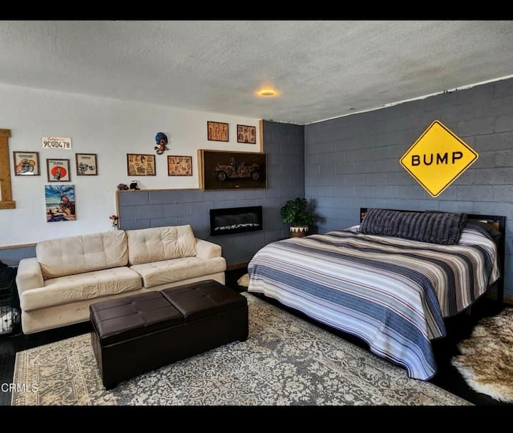 ห้องมาสเตอร์สวีทเตียงคิงไซส์ชั้นล่างพร้อมเตาผิงไฟฟ้าและโซฟาสบายๆ