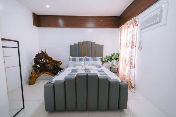 ห้องนอนสว่างและผ่อนคลายพร้อมเตียงควีนไซส์ที่อบอุ่น หมอนนุ่มและผ้าปูที่นอนระดับพรีเมียม และต้นไม้ในอาคารที่ช่วยทำให้อากาศบริสุทธิ์ เตรียมพร้อมอย่างพิถีพิถันด้วยสิ่งของจำเป็นและสัมผัสการต้อนรับ - เหมาะสำหรับการพักผ่อนหลังจากสำรวจเซบู
