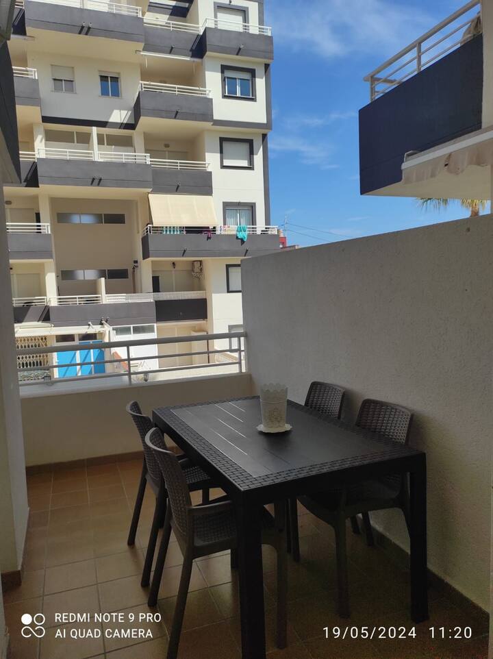 Mesa en la terraza para cenar al fresco con la piscina al fondo.