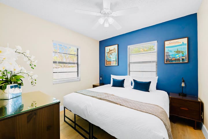 A calm Ocean State Park–inspired bedroom themed around Biscayne Bay, offering a king bed or two twins. Solid wood bedside tables, USB-equipped lamps, & a deep blue accent wall with two state park posters create a relaxed coastal retreat.