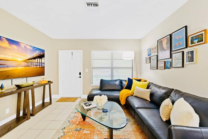 A cozy living room showcasing a high-quality leather L-shaped sectional, perfectly positioned by a large window that fills the space with natural Florida sunshine.