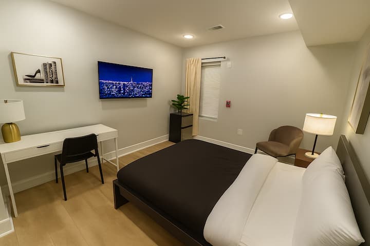 חדר שינה ראשי עם מיטת קווין סייז, טלוויזיה עם מסך שטוח, שולחן עבודה וחדר רחצה פרטי.