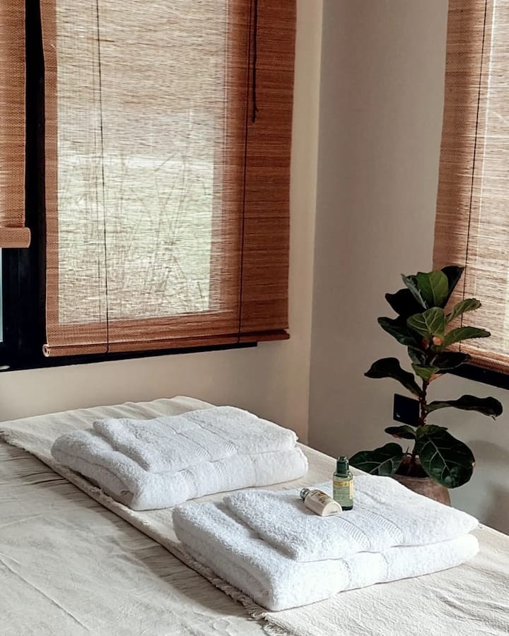 ห้องนอนหลักพร้อมเตียงคู่ตู้เสื้อผ้าเก้าอี้นวมเดี่ยวและหน้าต่างบานใหญ่พร้อมกระจก 2 ชั้น ห้องนี้มีพัดลมเพดาน