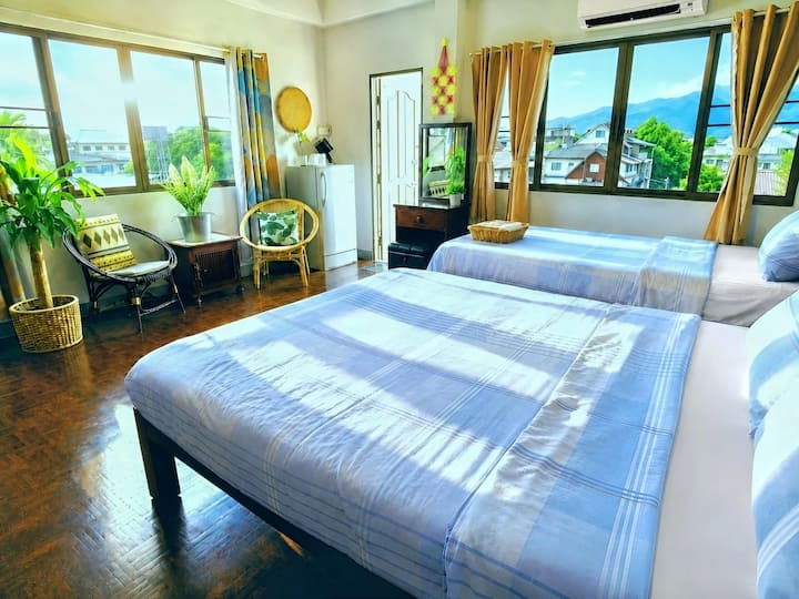 Bright corner room with a tall ceiling, two windows, a private balcony, and mountain views.